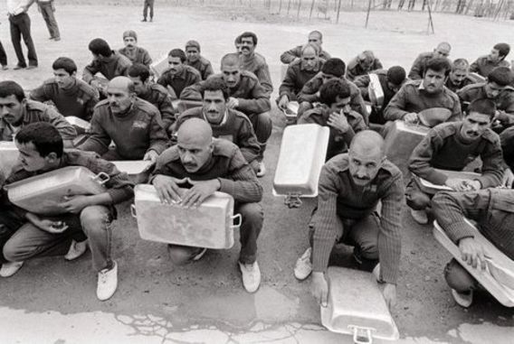  2 آوریل 1985 - اسرای جنگی ایرانی در اردوگاه رمادی عراق در انتظار دریافت غذای روزانه نشسته اند. 
