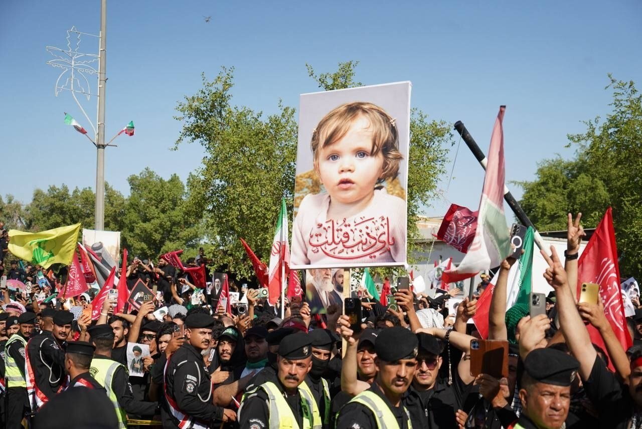 عکسی از نوه رهبر شهید بر روی دستان عزاداران عراقی